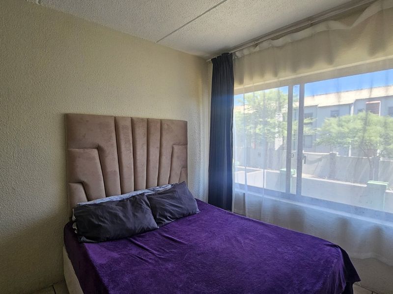 A bedroom featuring a large window that allows for natural light and a built-in cupboard for storage.