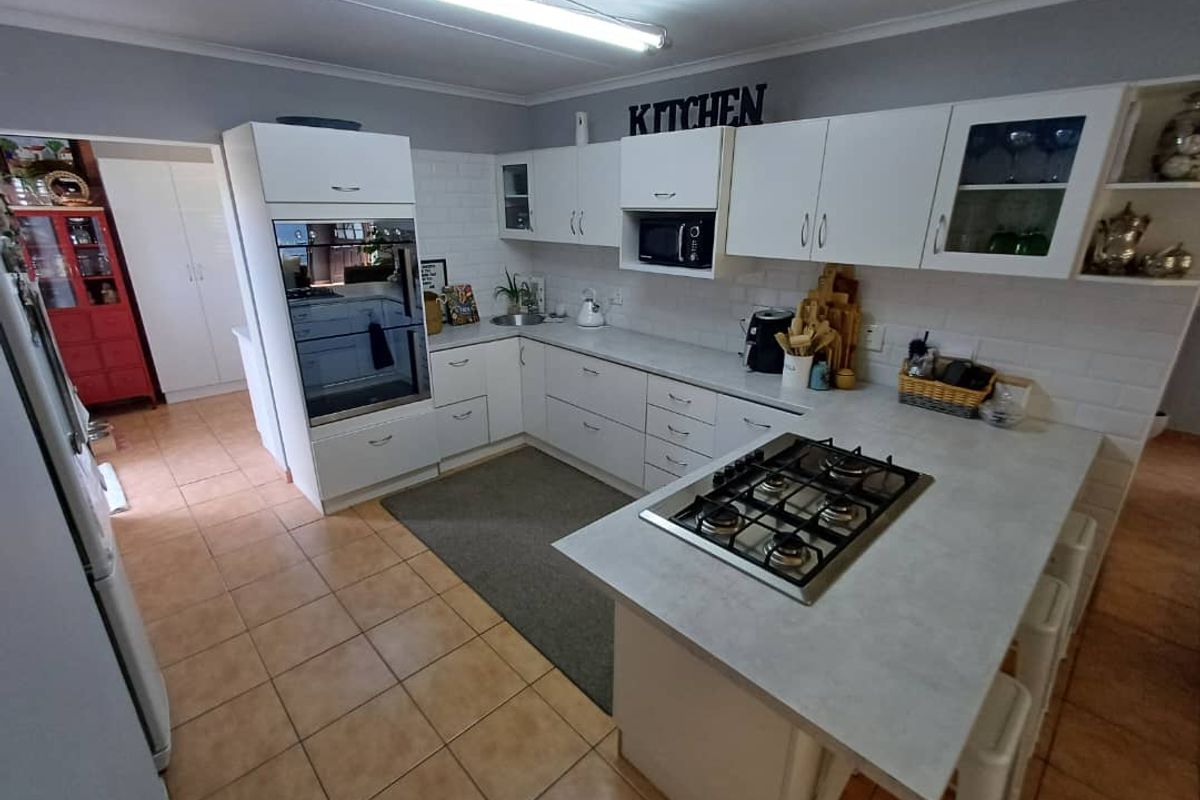 A functional kitchen featuring white cabinetry, a built-in oven, a gas hob on the peninsula, and tiled flooring.