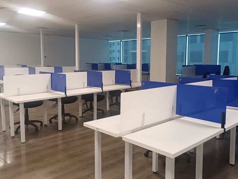 A spacious open-plan office area featuring laminate flooring, suspended ceilings with recessed lighting, and large windows with blinds providing ample natural light.