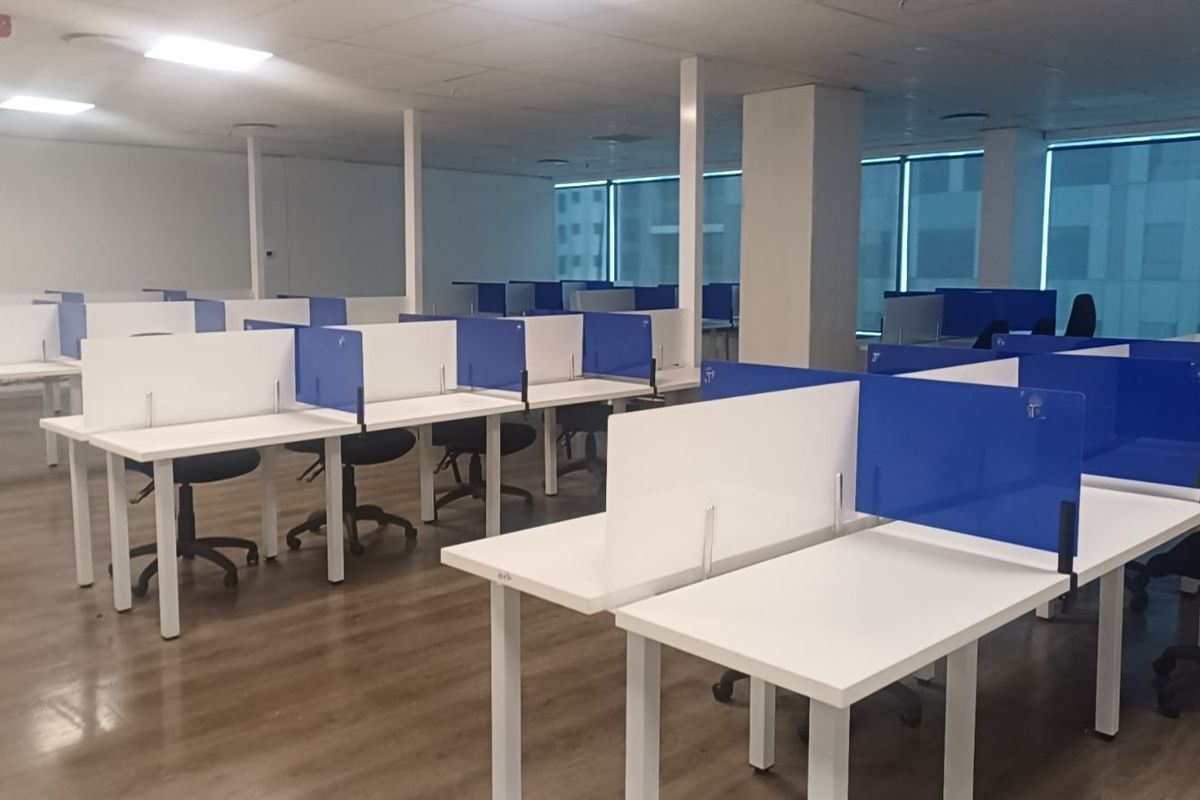 A spacious open-plan office area featuring laminate flooring, suspended ceilings with recessed lighting, and large windows with blinds providing ample natural light.