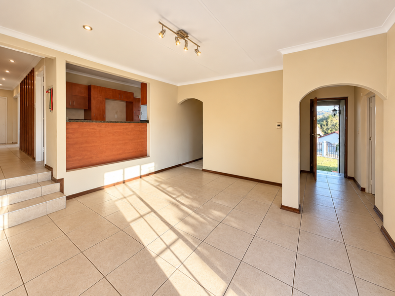 Spacious open-plan living area featuring tiled floors, arched doorways, and a pass-through kitchen counter, offering a bright and versatile layout.