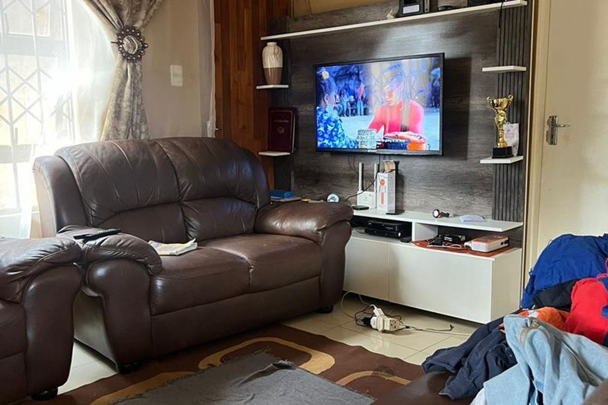 A living room featuring a built-in media unit and tiled flooring, offering a functional space for relaxation.