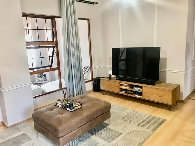 A cozy living room featuring laminate flooring, classic chair rail molding, and a large timber-framed window allowing natural light into the space.
