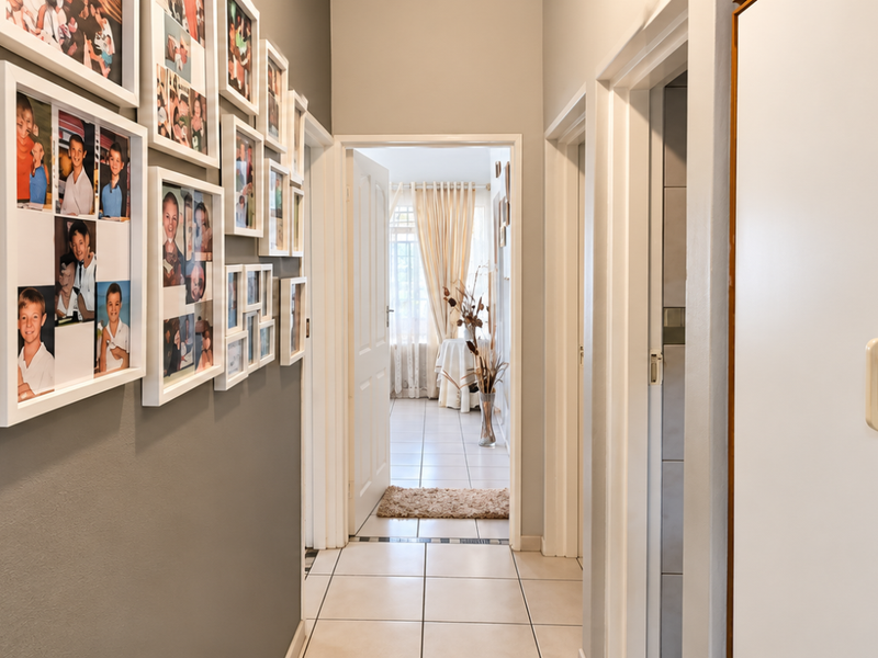 A well-maintained hallway featuring tiled flooring and a built-in storage cupboard, providing access to adjacent rooms within the home.