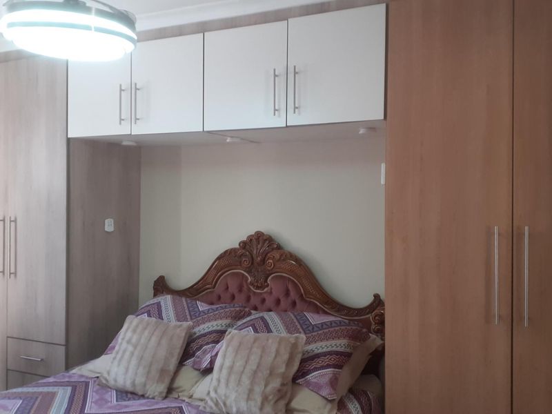 A bedroom featuring extensive built-in wooden cupboards and overhead storage cabinets, providing ample integrated storage space.