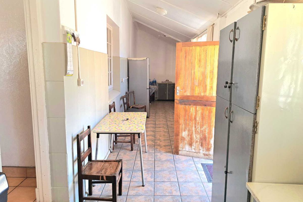 A functional kitchen area featuring tiled flooring, wall splashbacks, and built-in cabinetry, offering potential for modernization and aesthetic updates.