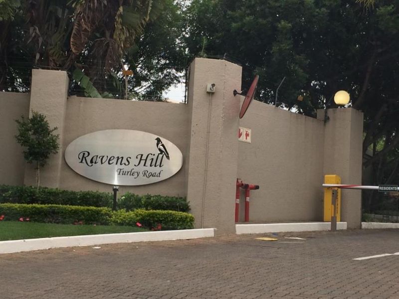 Entrance view of Ravens Hill complex on Turley Road, featuring a secure boom gate, perimeter wall with electric fencing, and landscaped garden.