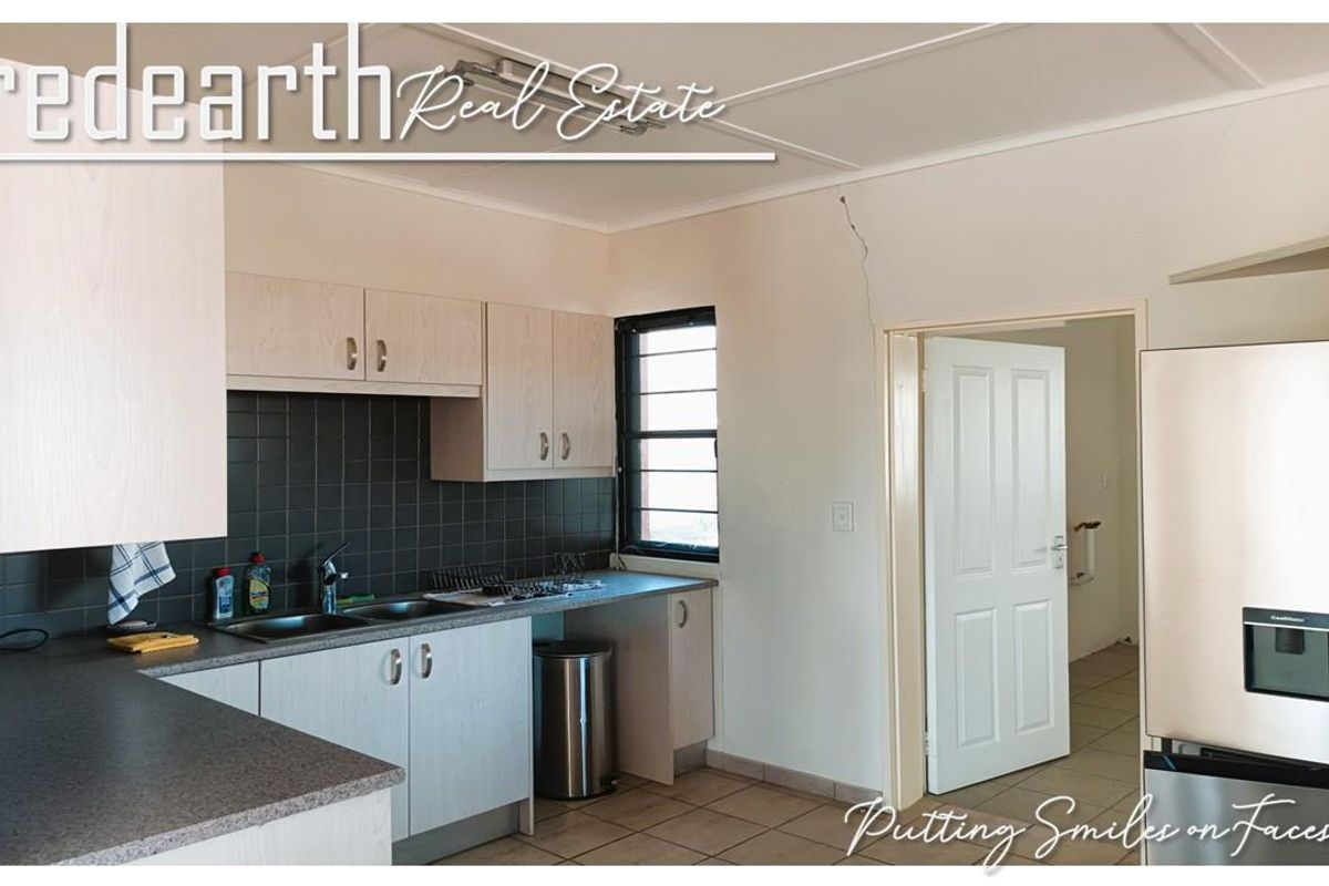 Functional kitchen featuring laminate cabinetry, tiled splashback, and double bowl sink, with direct access to an adjacent room.