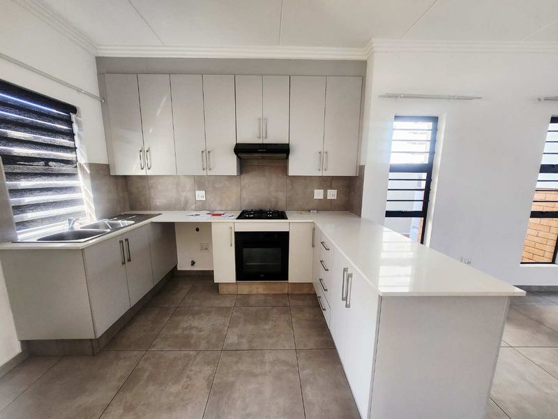 Modern kitchen featuring sleek cabinetry, stone countertops, gas hob, electric oven, and tiled flooring in a clean, contemporary layout.