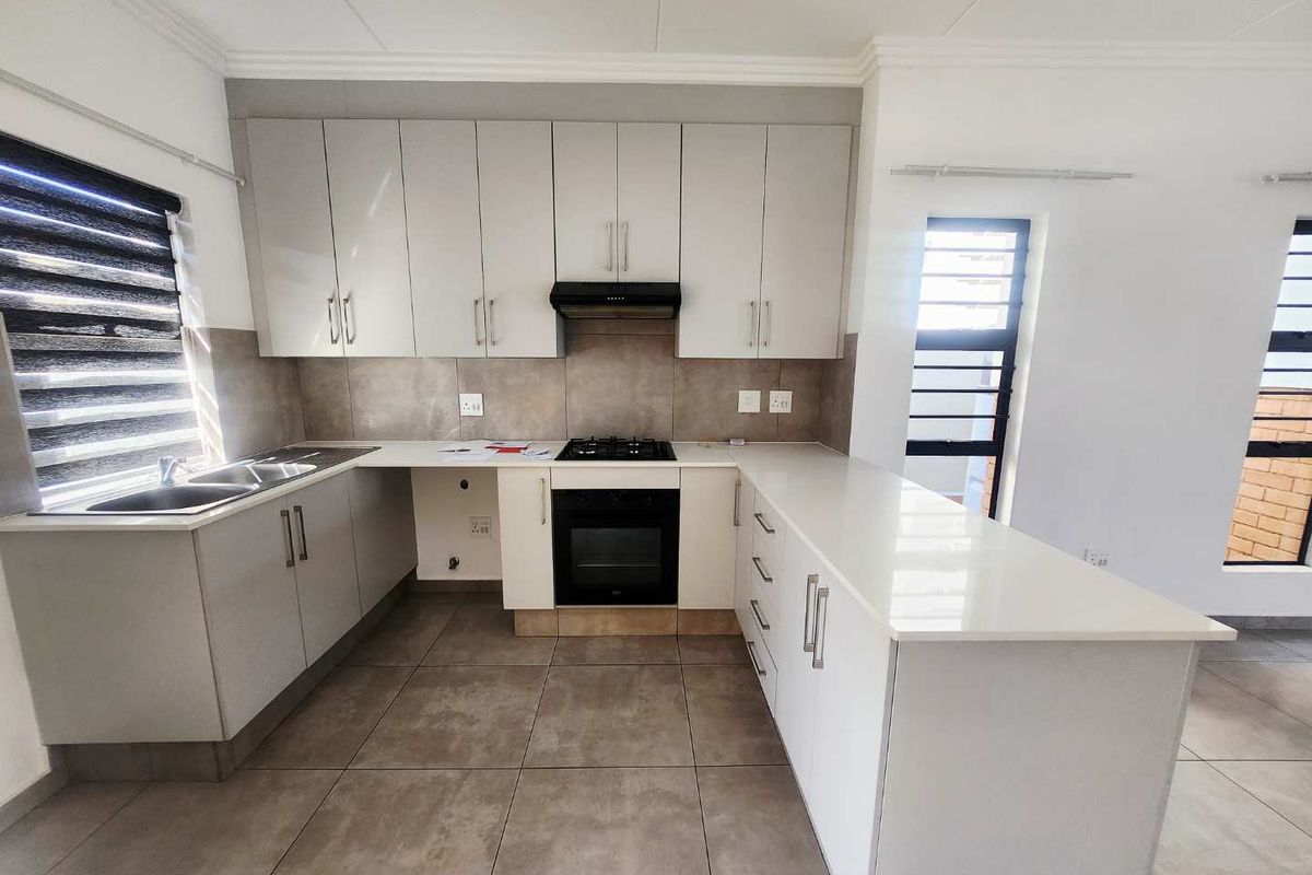 Modern kitchen featuring sleek cabinetry, stone countertops, gas hob, electric oven, and tiled flooring in a clean, contemporary layout.
