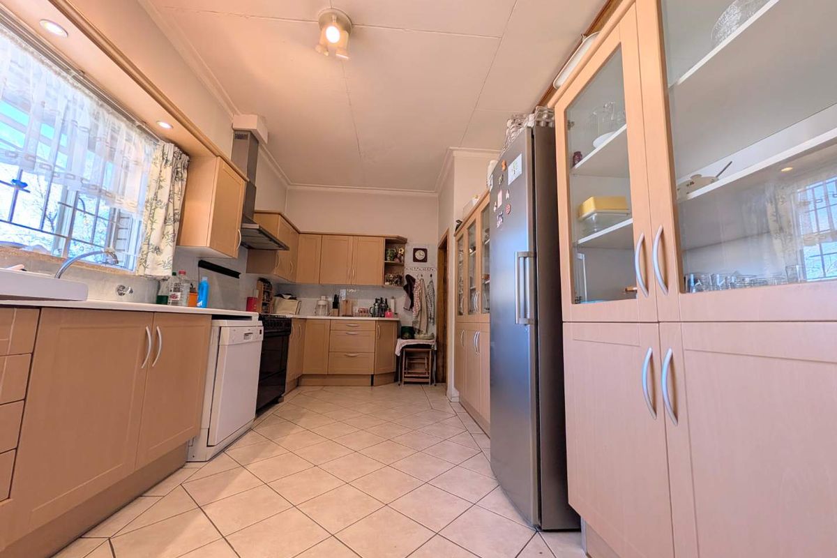 A functional kitchen featuring light wood cabinetry, tiled flooring, ample storage space, and integrated display cabinets, offering a practical layout for daily use.