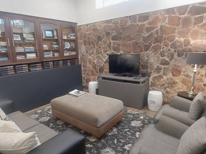 A cozy living room featuring a distinctive stone feature wall and integrated wooden cabinetry, providing a warm and character-filled space.