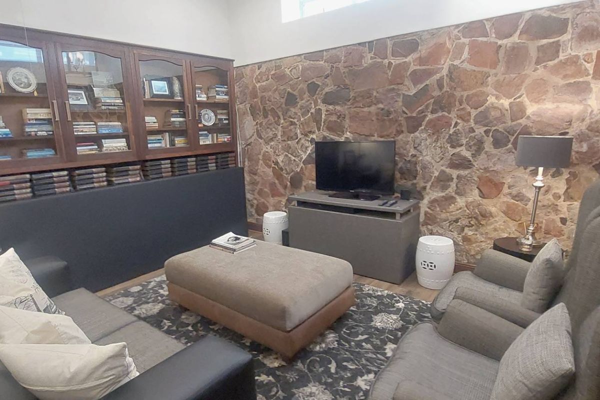 A cozy living room featuring a distinctive stone feature wall and integrated wooden cabinetry, providing a warm and character-filled space.