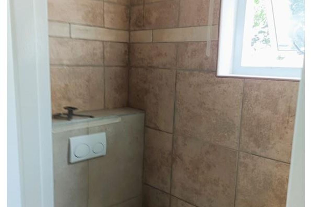 A compact guest bathroom featuring a wall-mounted toilet with a concealed cistern and a small wall-hung basin.