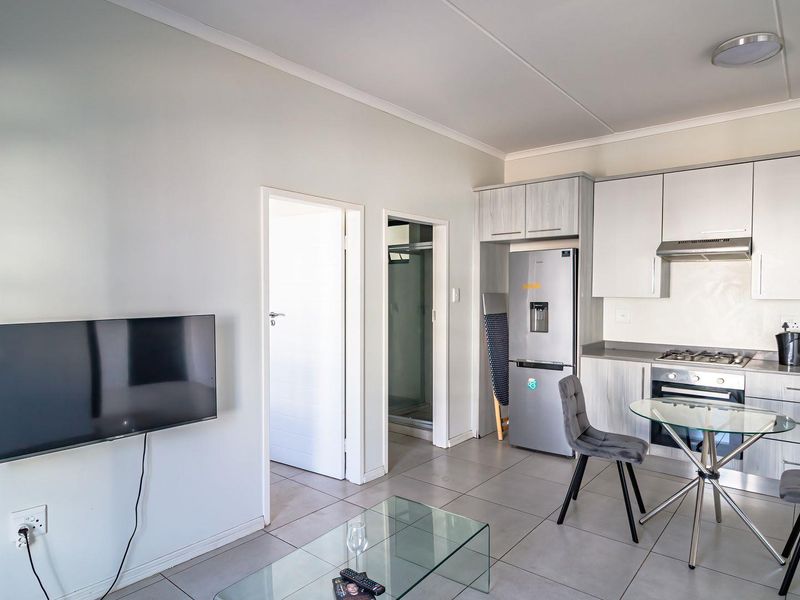 Open-plan living area featuring a modern kitchen with built-in cabinetry, gas hob, extractor fan, and tiled flooring throughout.