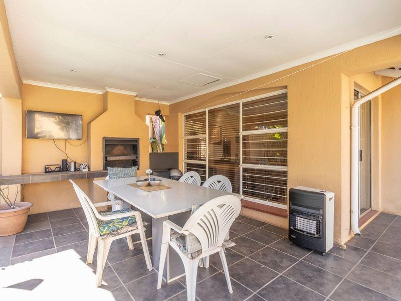 Covered patio area featuring a built-in braai, tiled flooring, and direct access to the interior through sliding glass doors.