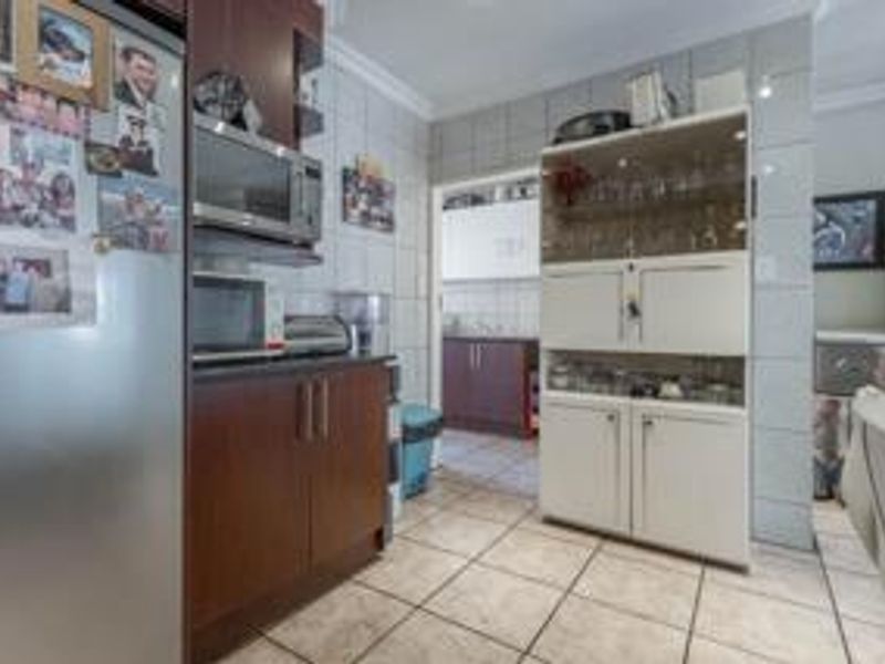 A functional kitchen area featuring tiled walls and flooring with built-in cabinetry and integrated microwave space, offering a practical layout for daily use.