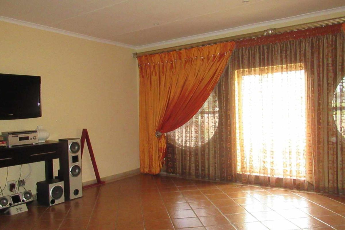 A living room featuring tiled flooring and large circular windows with curtains, providing natural light and a view of the exterior.
