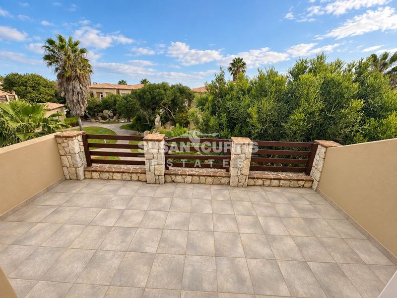 A spacious balcony featuring tiled flooring, stone-clad pillars, and a timber slat balustrade, offering an open view of the surrounding estate grounds.