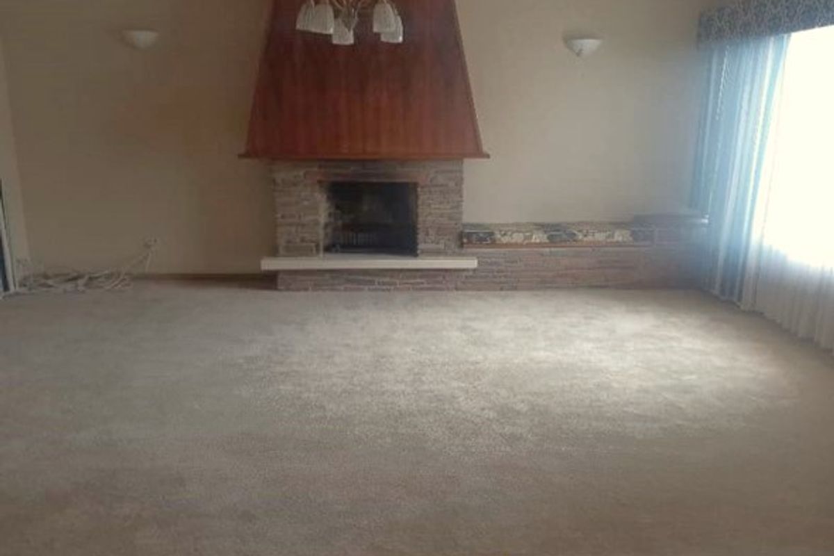 Spacious living room featuring a prominent fireplace with stone detailing, built-in bench seating, and a combination of tiled and carpeted flooring.