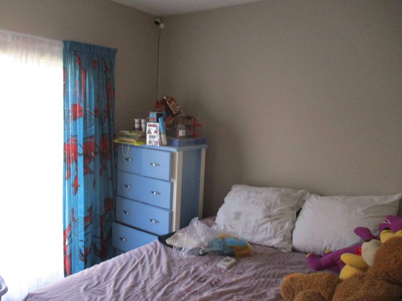 A bedroom featuring neutral wall paint and a mounted security camera, providing a functional space with natural light access.