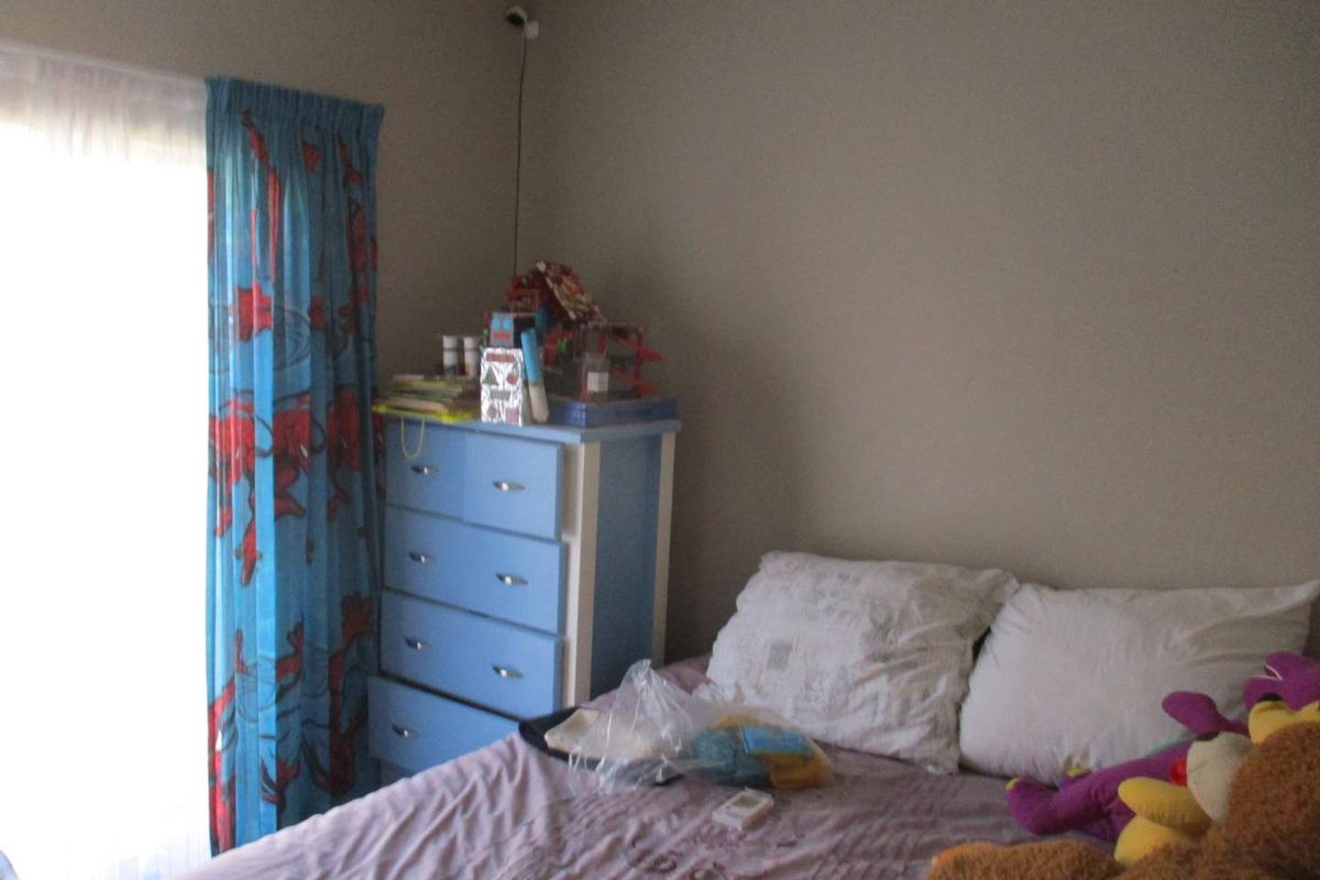 A bedroom featuring neutral wall paint and a mounted security camera, providing a functional space with natural light access.