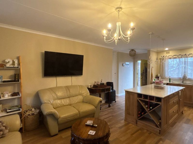 Open-plan living and kitchen area featuring a central island with built-in wine storage, laminate flooring, and neutral wall finishes.