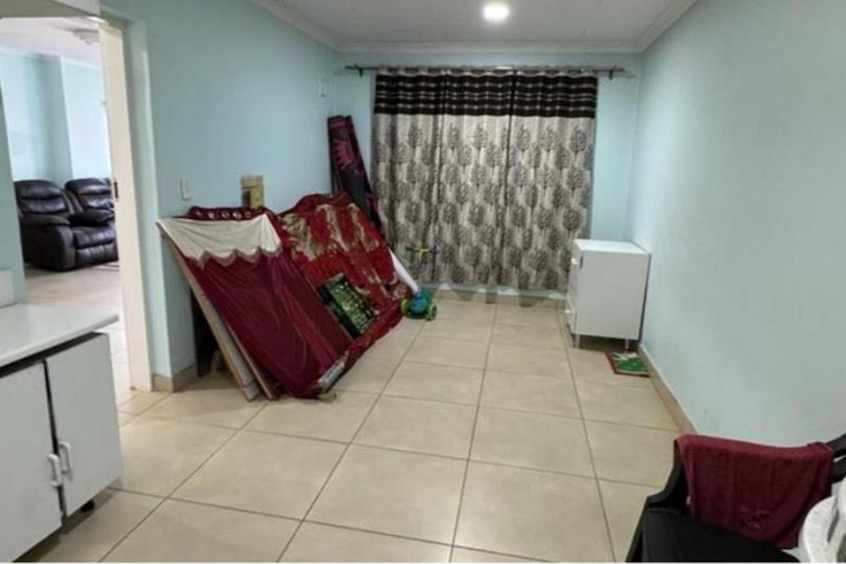 A living area featuring neutral tiled flooring and recessed ceiling lighting, offering a functional space ready for personalization and updated interior styling.