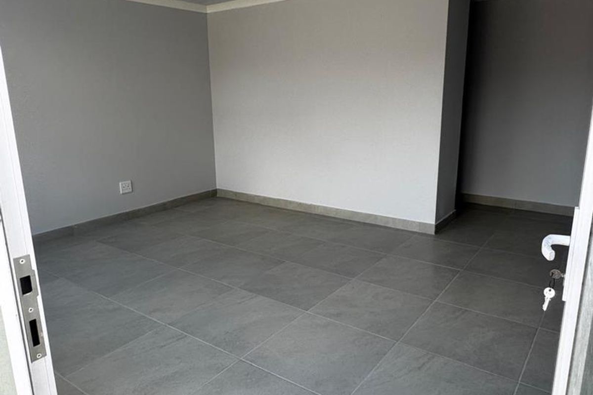 A clean, empty interior space featuring modern grey floor tiles, neutral painted walls, and a white tongue-and-groove ceiling with recessed lighting.
