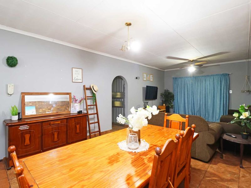 Open plan living and dining area featuring tiled flooring, a ceiling fan, and a distinctive arched doorway leading to other parts of the home.