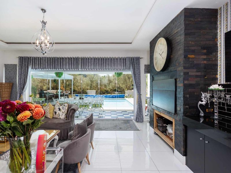 Spacious living room featuring a striking stacked stone fireplace, polished porcelain flooring, and seamless indoor-outdoor flow through large sliding glass doors to the pool area.