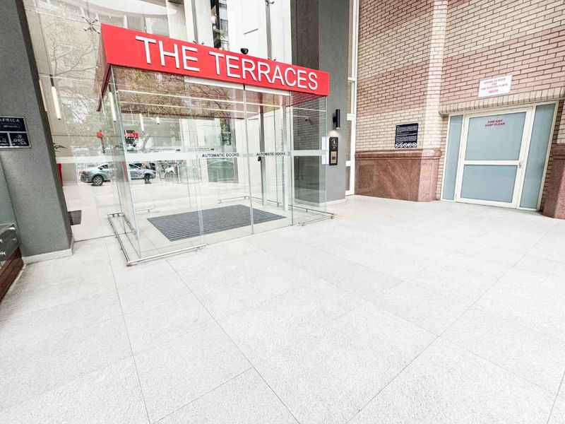 Main entrance area of The Terraces office building, featuring modern glass automatic doors, clean tiled flooring, and professional brick exterior finishes.
