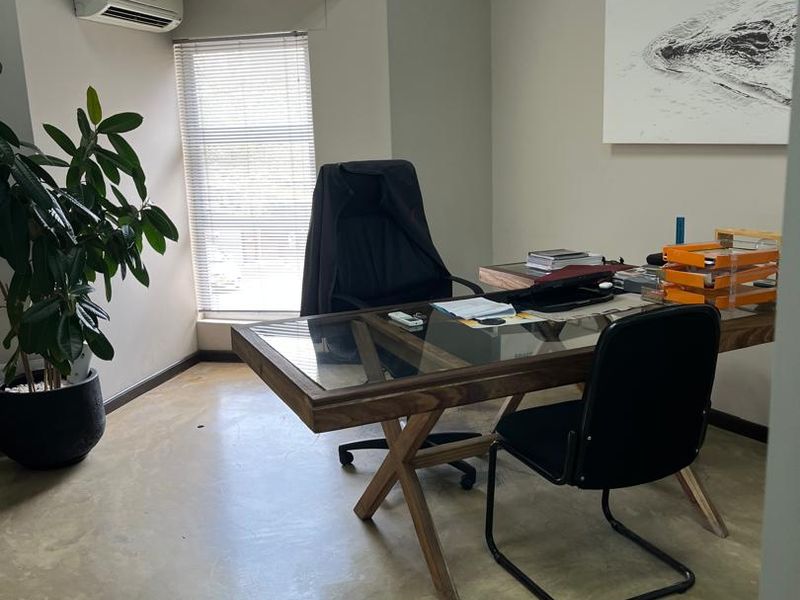 A professional office space featuring polished concrete floors, clerestory windows for natural light, and a wall-mounted air conditioning unit.