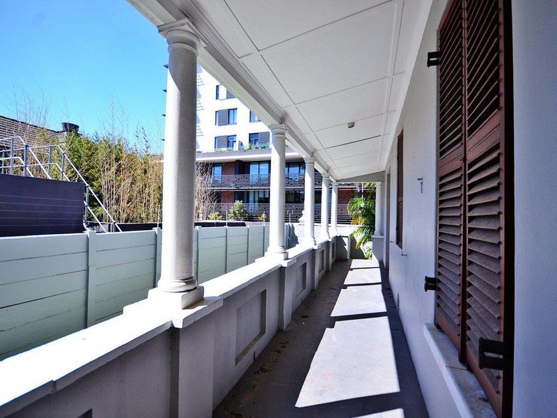 A covered veranda featuring classical columns and timber shutters, providing a sheltered outdoor space with a view of the surrounding area.