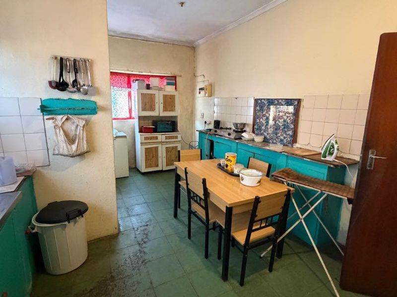 A dated kitchen featuring built-in cabinetry, tiled splashbacks, and tiled flooring, offering significant potential for modernization and renovation.