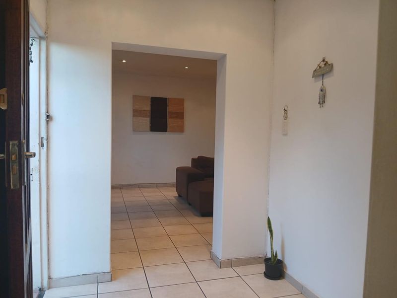 Entrance hallway with tiled flooring and recessed lighting, leading into an open-plan living area.