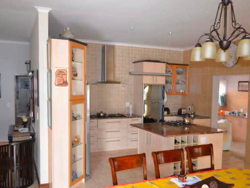 Open plan kitchen featuring built-in cabinetry, a central island with a gas hob, and a tiled splashback, seamlessly connecting to the dining area.
