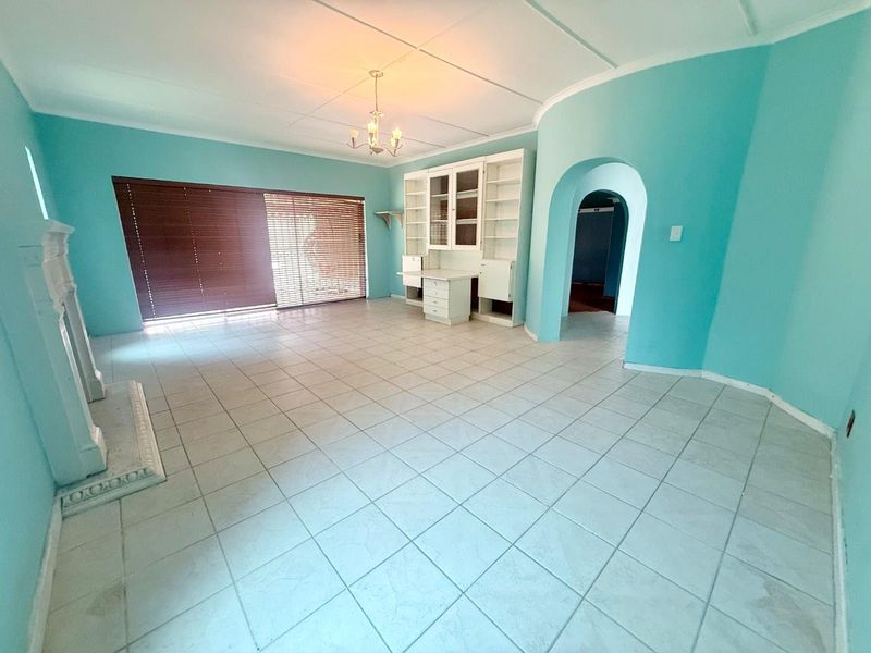 Spacious living room featuring tiled flooring, a built-in shelving unit, a fireplace, and an arched entryway leading to adjacent spaces.