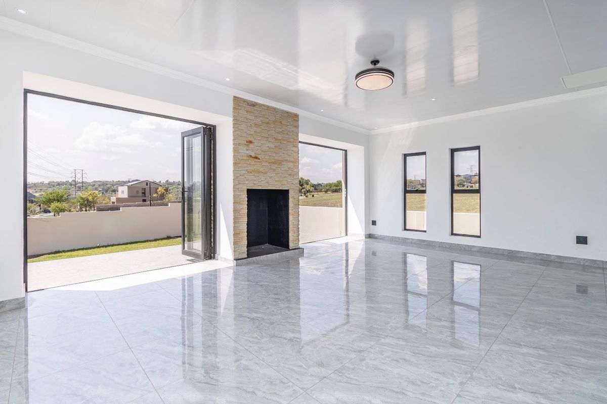 Spacious, modern living area featuring polished tile floors, a striking stone-clad fireplace, and large bi-fold doors opening to an outdoor patio.