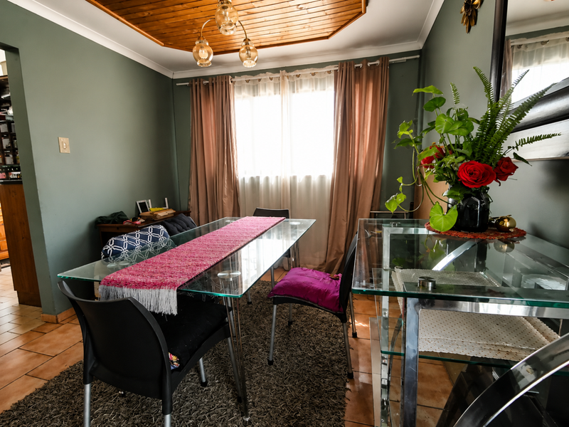 Dining room featuring a distinctive timber-clad ceiling, tiled flooring, and neutral wall tones, providing a functional space for family meals.