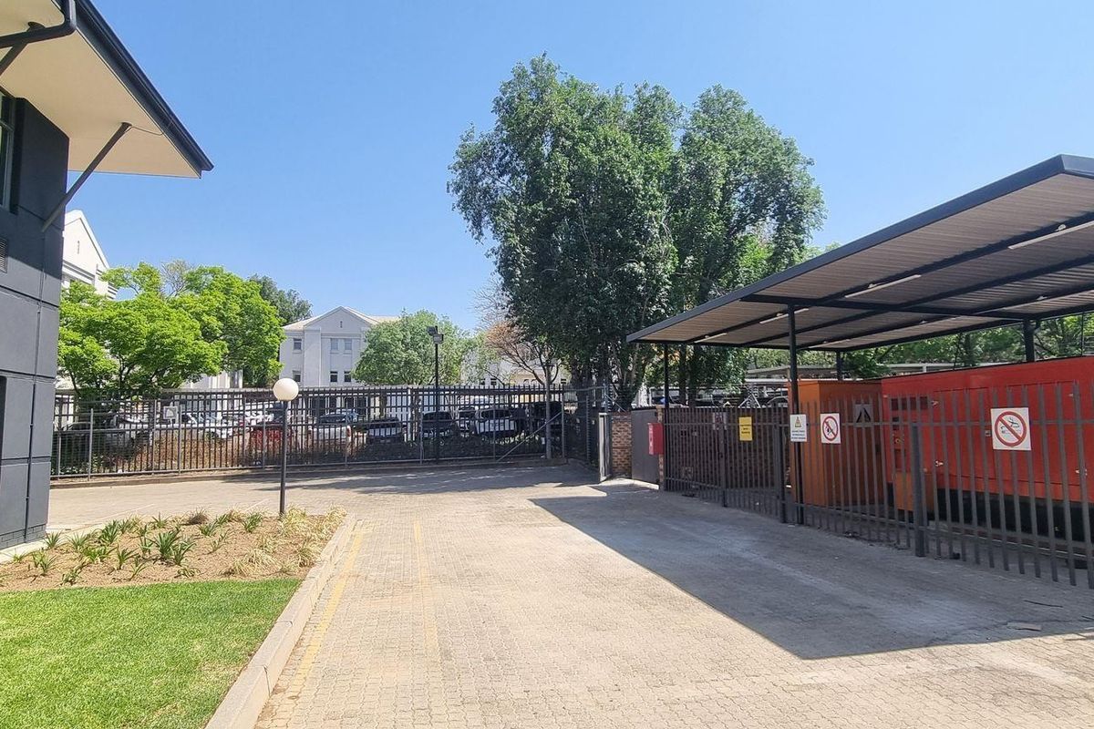Exterior view of the office property grounds featuring a paved driveway, landscaped garden area, and a covered generator enclosure.