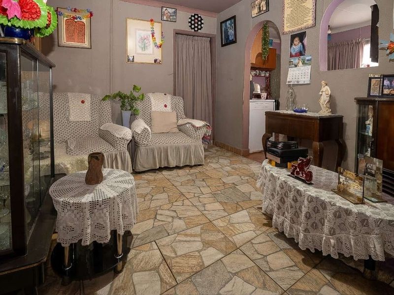 A living room featuring stone-style tiled flooring and an arched doorway leading to an adjacent space.