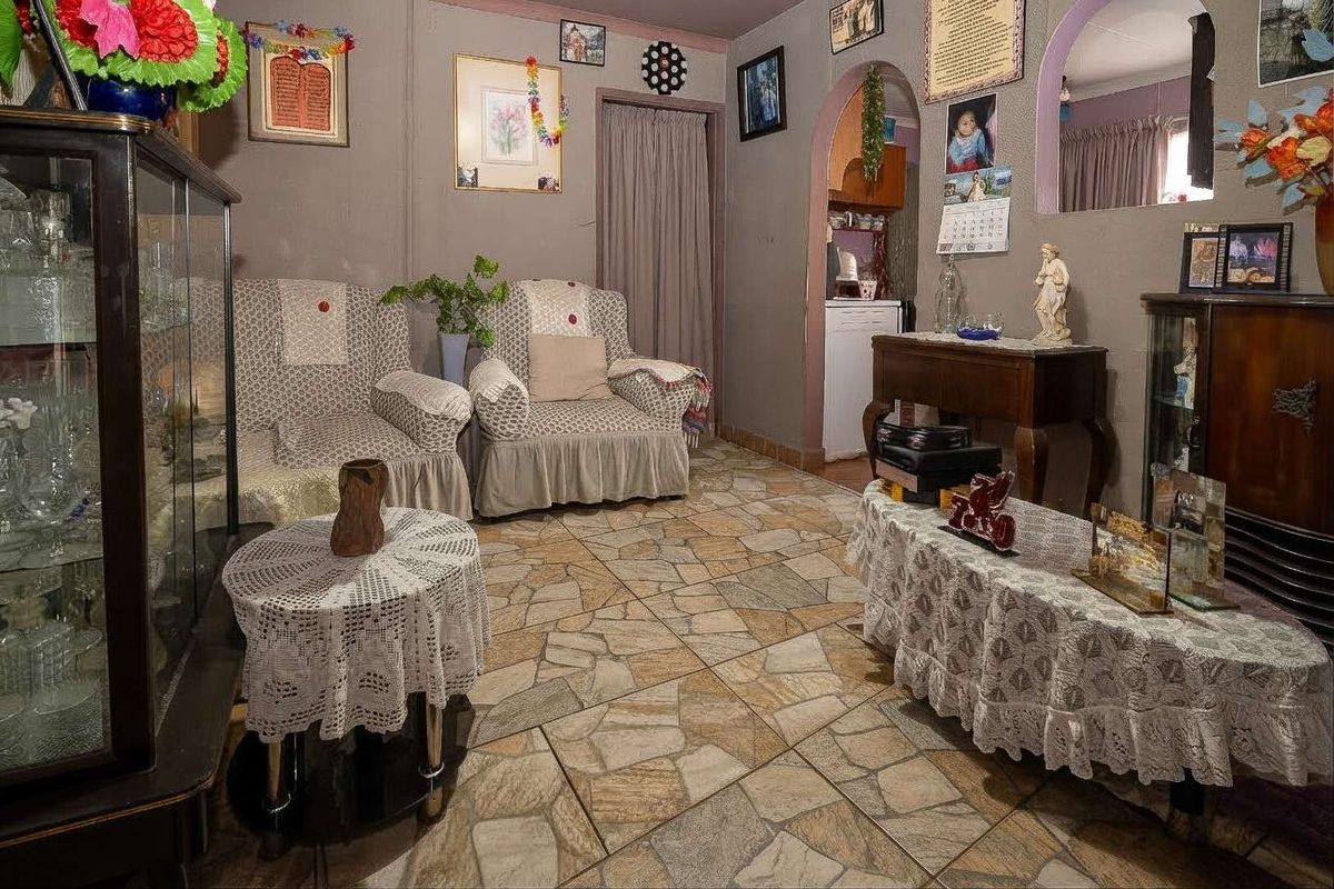 A living room featuring stone-style tiled flooring and an arched doorway leading to an adjacent space.