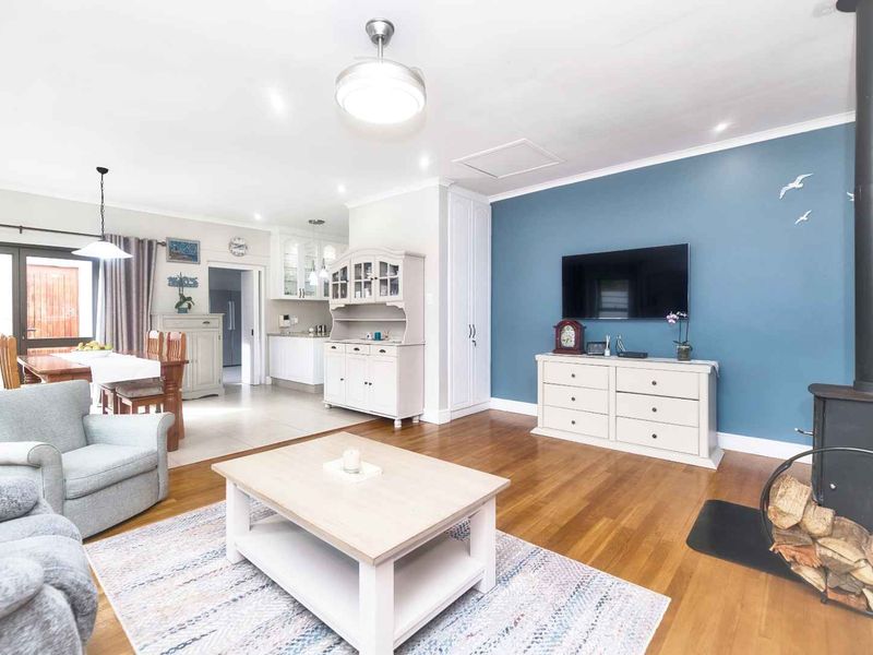 Spacious open-plan living and dining area featuring hardwood floors, a wood-burning stove, and seamless flow into the adjacent kitchen space.