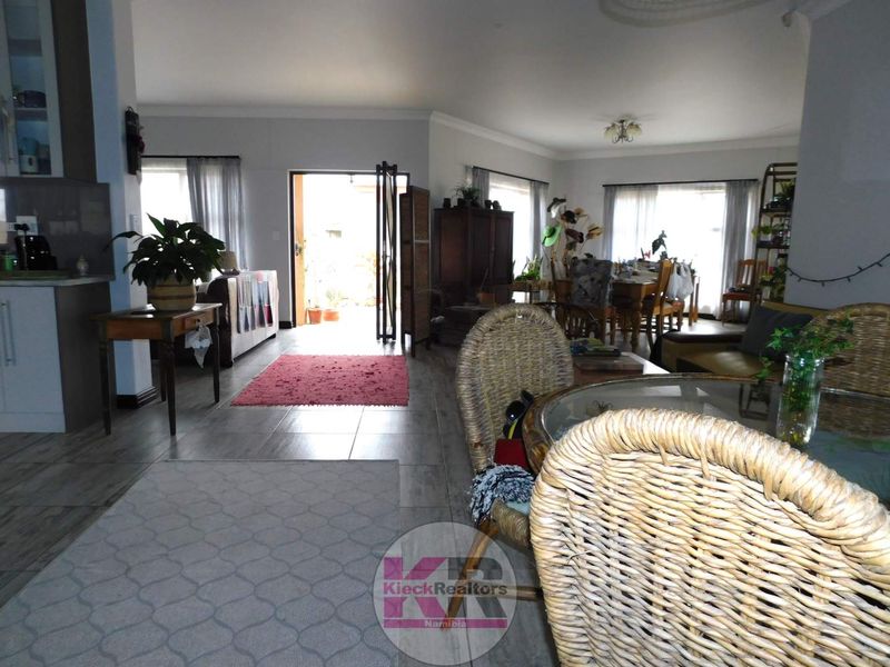 Spacious open-plan living and dining area featuring tiled flooring, neutral walls, and direct access to an outdoor patio through a sliding door.