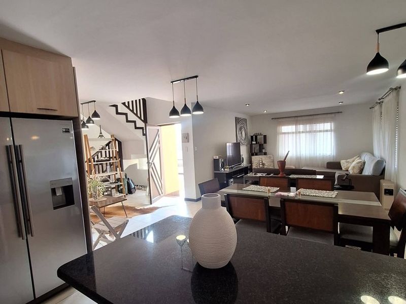 Spacious open-plan living area featuring a modern kitchen with granite countertops, dining space, and a staircase leading to the upper level.