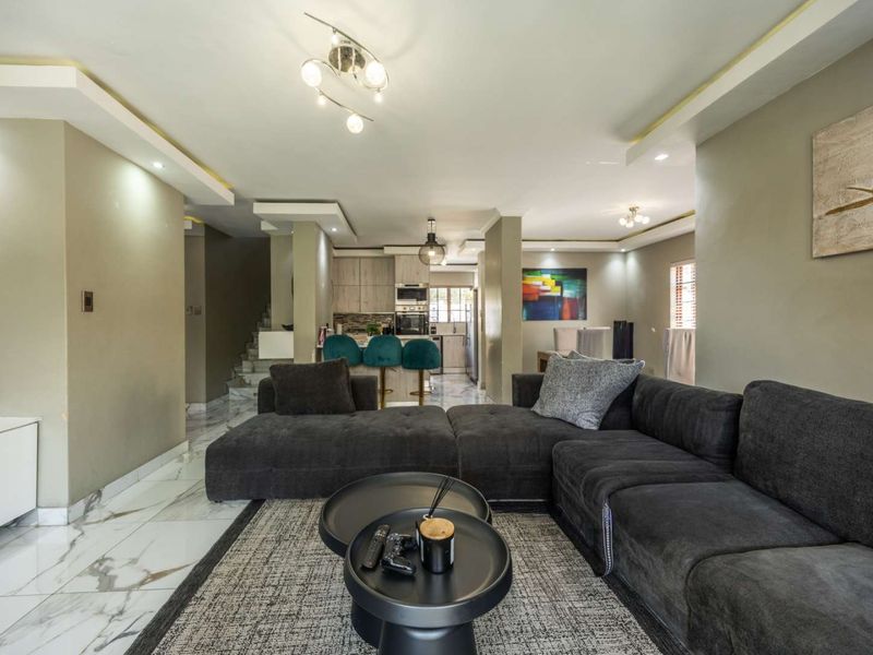 Spacious open-plan living area featuring modern marble-look flooring, recessed ceiling lighting, and a seamless transition to the kitchen space.