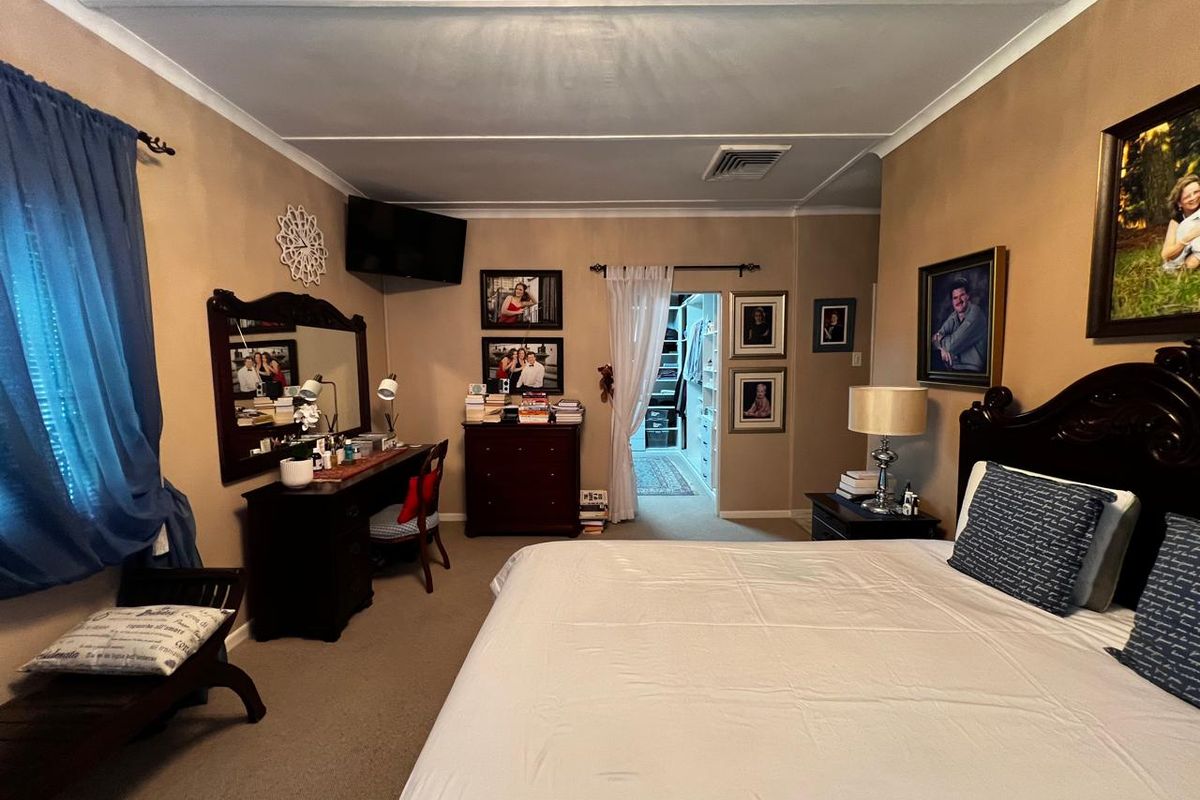 Spacious bedroom featuring neutral walls, carpeted flooring, and an adjoining walk-in closet with built-in shelving.