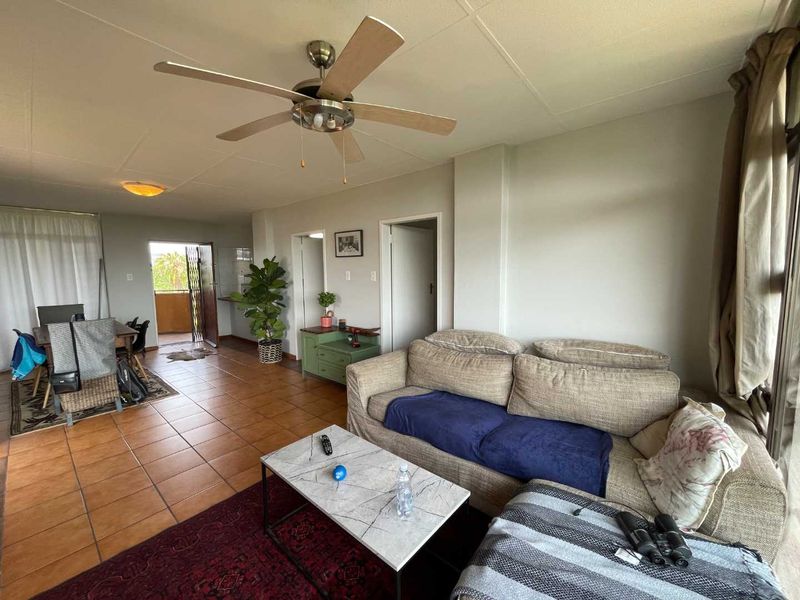 Open plan living and dining area featuring tiled flooring, a ceiling fan, and direct access to an outdoor balcony.