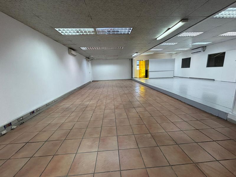 Spacious industrial utility area featuring tiled flooring, suspended ceilings with integrated lighting, and wall-mounted air conditioning units.